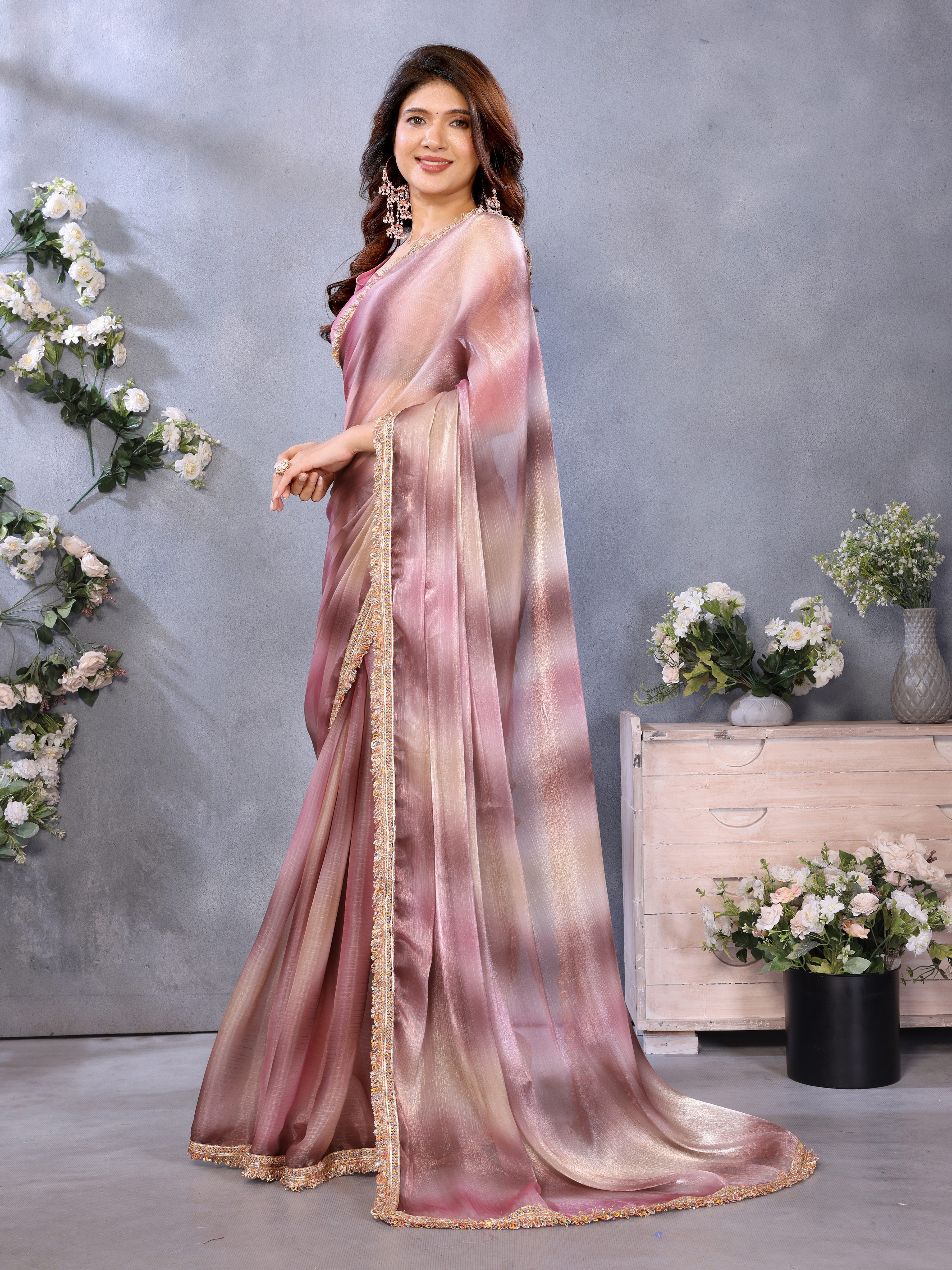 Woman wearing a pink and beige saree with a floral background